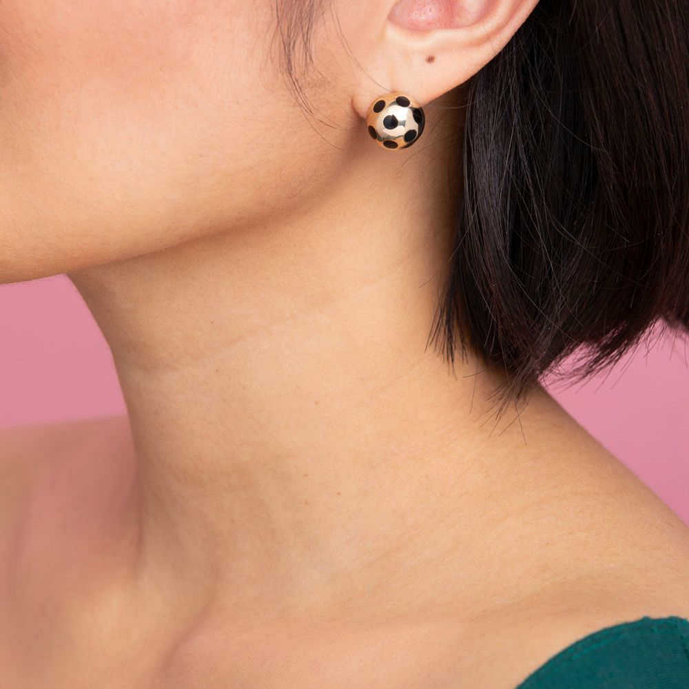 Rachel Quinn Jewelry pair of 14k yellow gold ball earring with black polka dots on model ear.