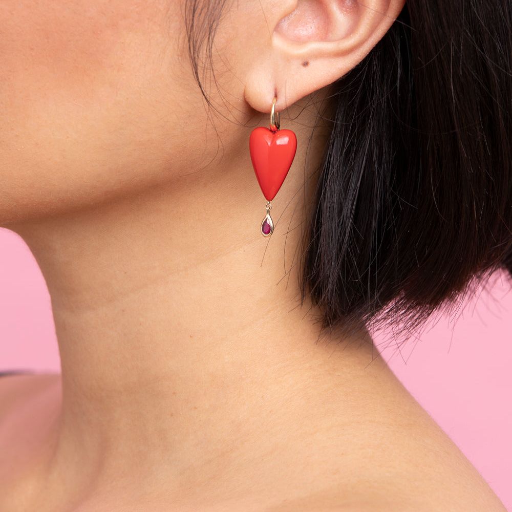 Rachel Quinn Jewelry hand-carved coral heart earring topped with 14K yellow ear wires with a bezel-set ruby droplet on female model ear