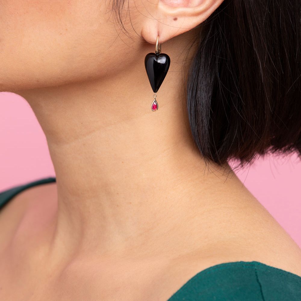 Rachel Quinn Jewelry hand-carved onyx heart earring topped with 14K yellow ear wires with a bezel-set ruby droplet on female model ear