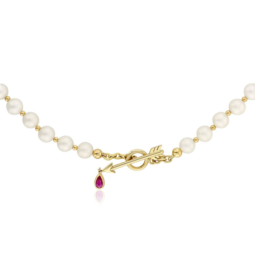 pearl necklace with yellow gold arrow clasp and ruby droplet from the arrow on a white background
