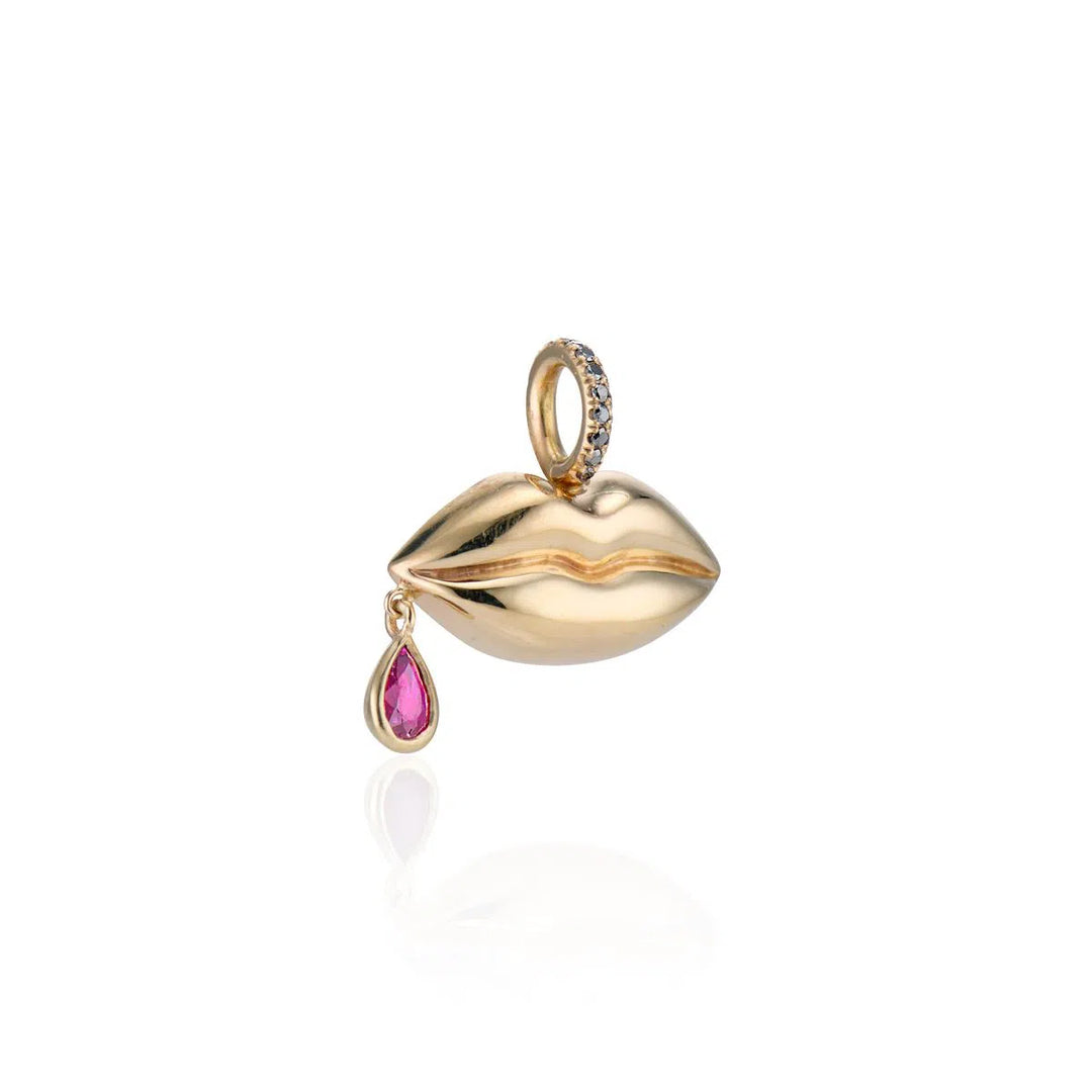angled view of gold lips with red ruby dangling on side of mouth charm on white background