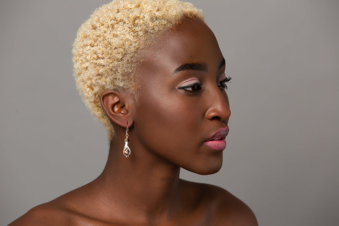 woman modeling Sterling silver hand earring gently hold a 14K solid rose gold heart with a yellow bail and ear wire