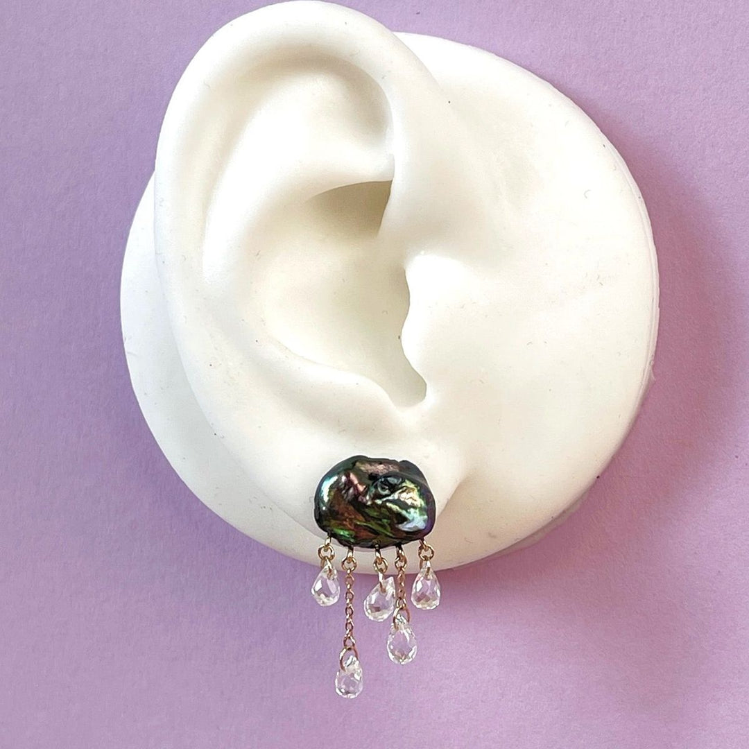 white ear shape one purple background with dark cloud-shaped pearl earring with 5 raindrops dangling below