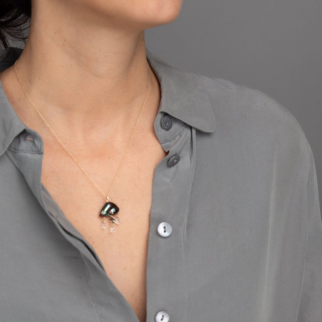 woman in grey modeling Peacock keshi pearl cloud electrified with a 14K yellow gold lightning bolt as a trio of white topaz rain down on gold chain necklace