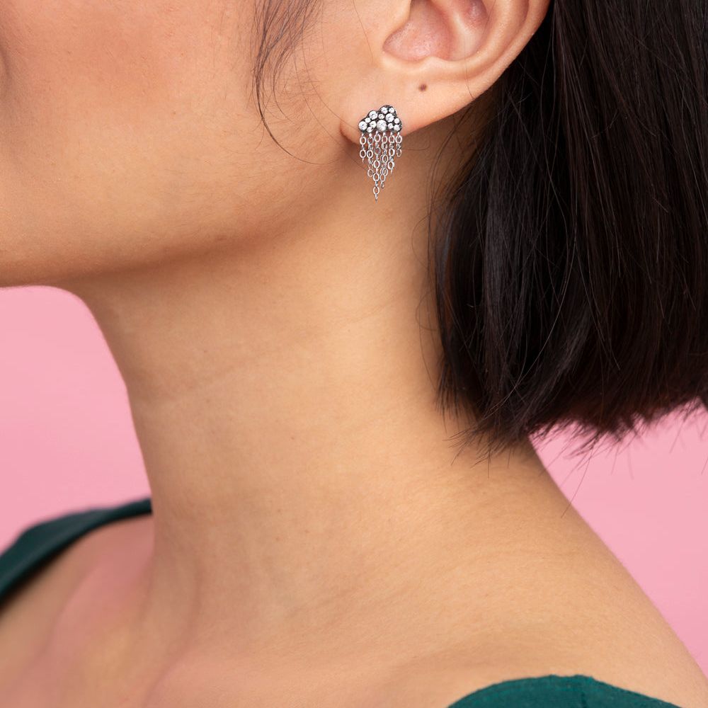 Rachel Quinn Jewelry black rhodium cloud shaped earring with pace set white sapphires on cloud and silver dangling chains shown on female model ear.