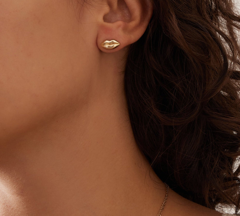 close up of a brunette woman's neck and ear wearing a small yellow gold lips stud