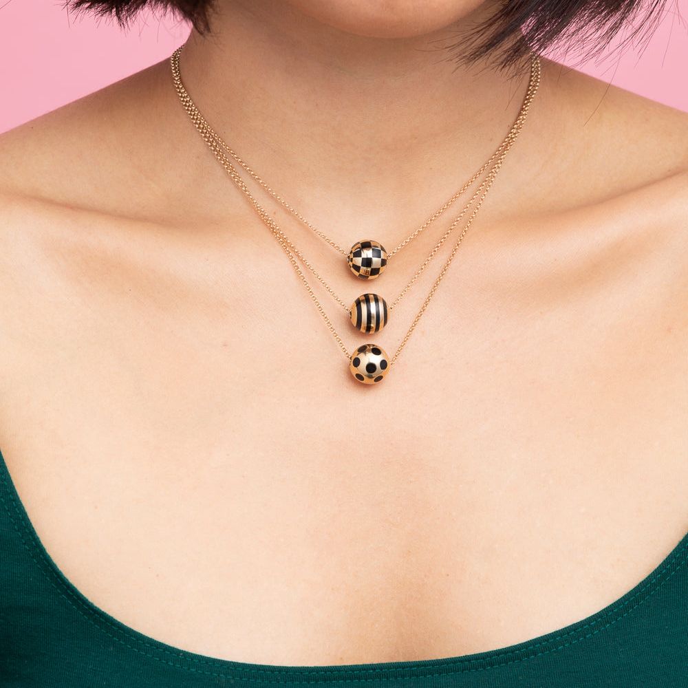 Rachel Quinn Jewelry model wearing 3 sphere gold and black pattern variations necklace on gold chains worn around models neck