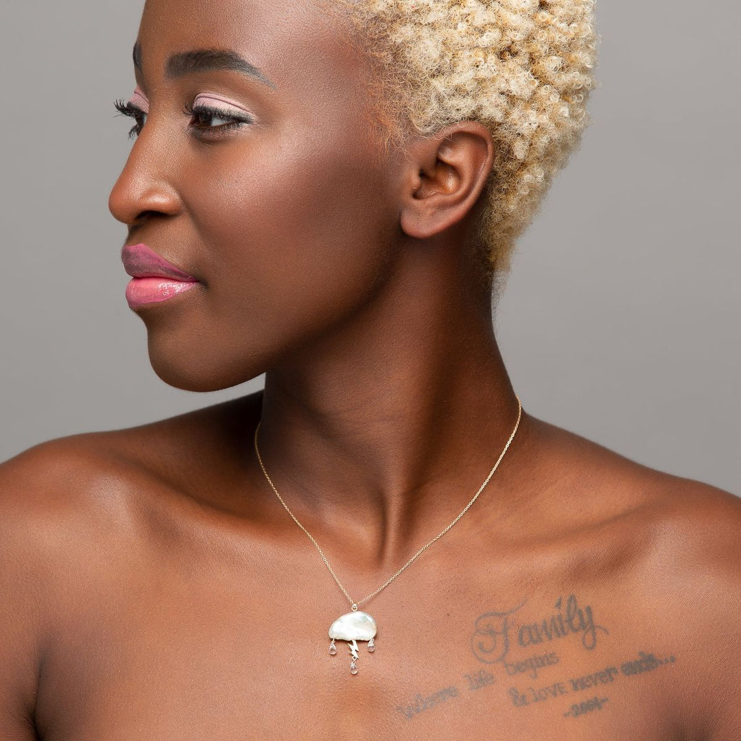 woman models White keshi pearl cloud electrified with a 14K yellow gold lightning bolt as a trio of white topaz rain down on gold chain necklace