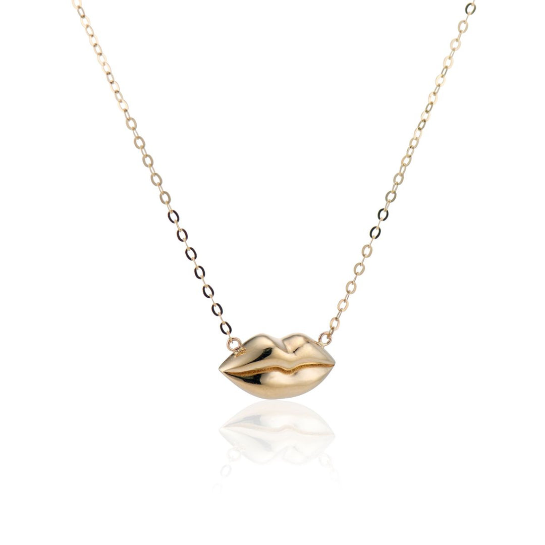 angled view of gold lips on a gold chain necklace with a white background