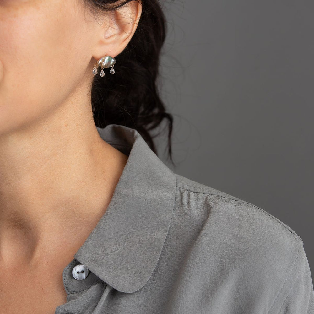 woman in grey modeling champagne keshi pearl earrings in cloud-like form with three white topaz dangling from the bottom with yellow gold components