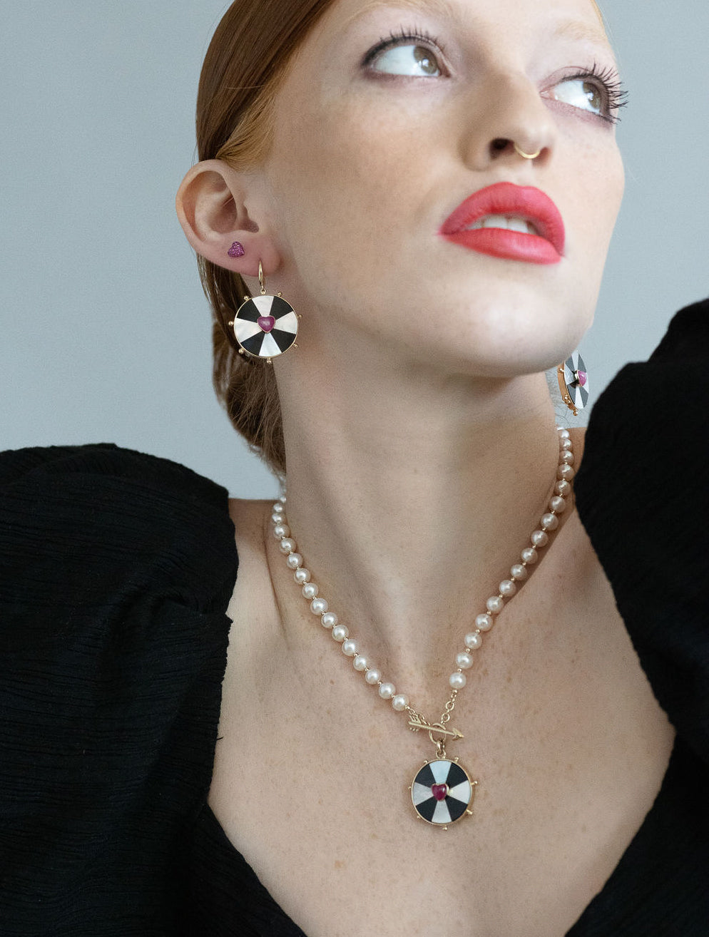 red head model wearing both the bullseye necklace and earrings on a grey background