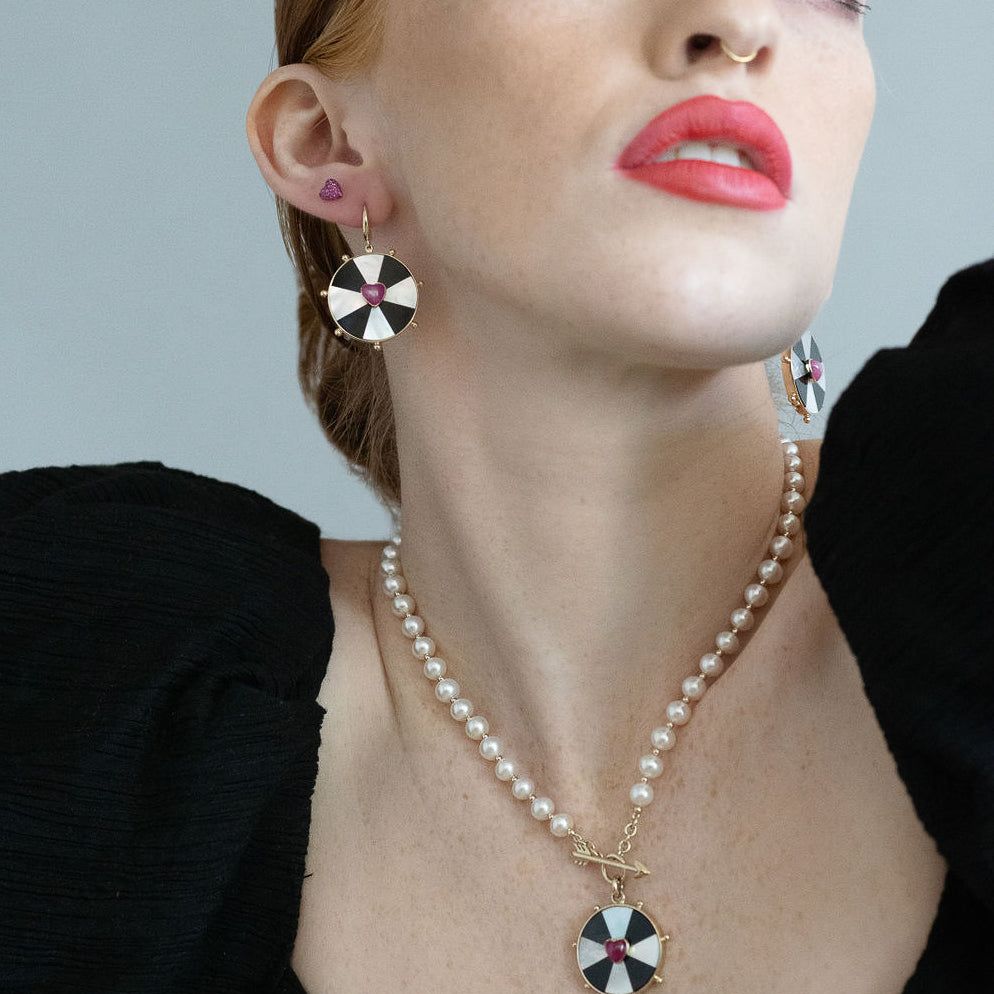 red head model wearing both the bullseye heart necklace and earrings 