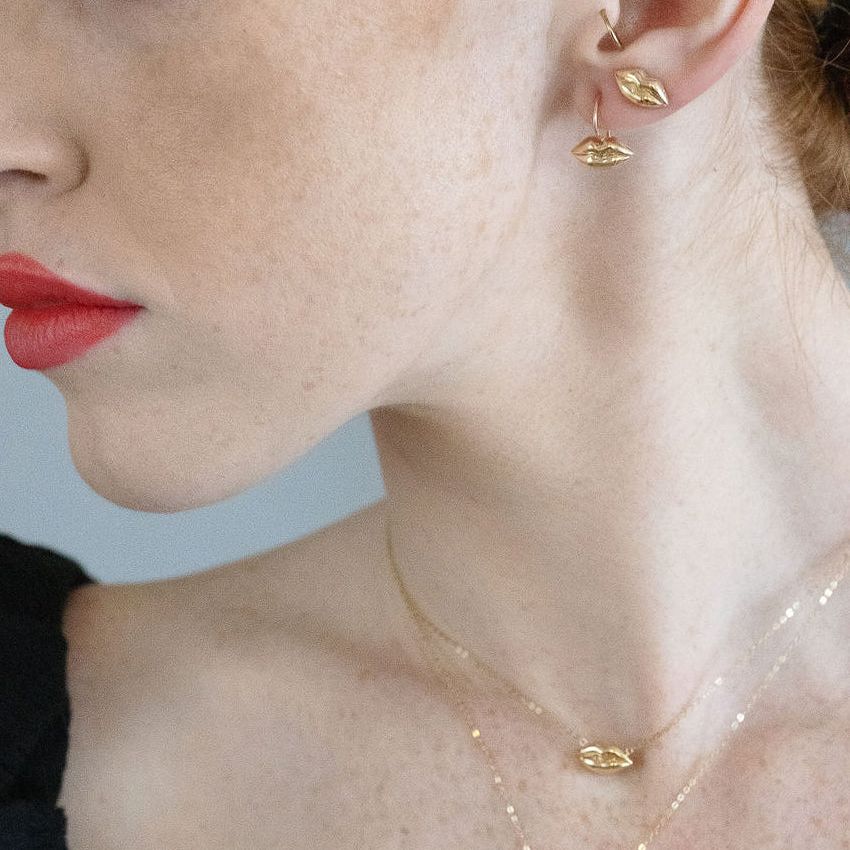 red head model wearing gold lips earrings and necklaces
