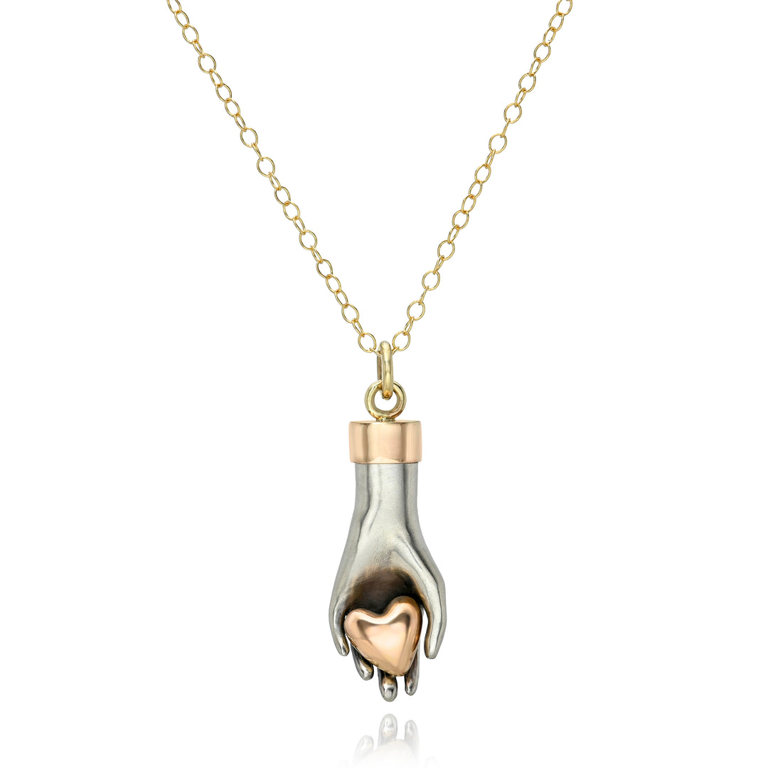 Yellow gold necklace with a silver hand and rose gold heart pendant on a white background