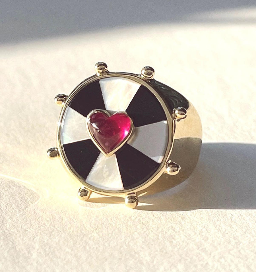 Yellow gold ring with black and white bullseye pattern and a pink heart set in the center