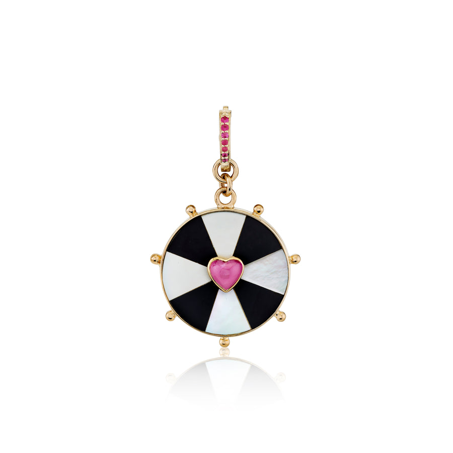 Round black and white bullseye with a pink heart set in the center in a yellow gold bezel with seven gold balls circling the boarder and a bail with 7 pink rubies set in the front
