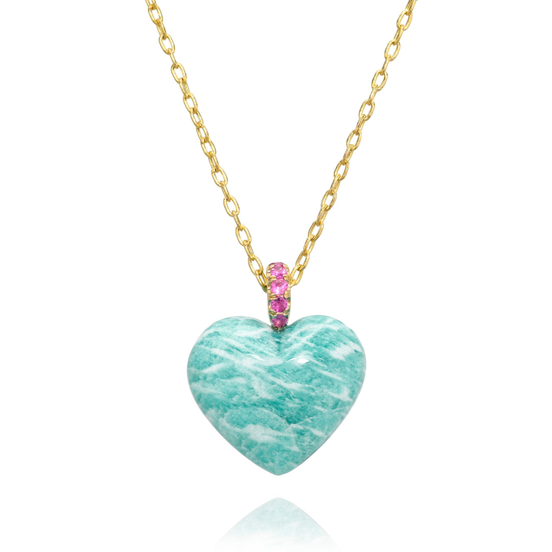 Heart-shaped blue with white streaks stone pendant on a gold chain with a pink gemstones bail against a white background