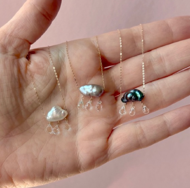 Three pearl necklaces on a hand with a pink background