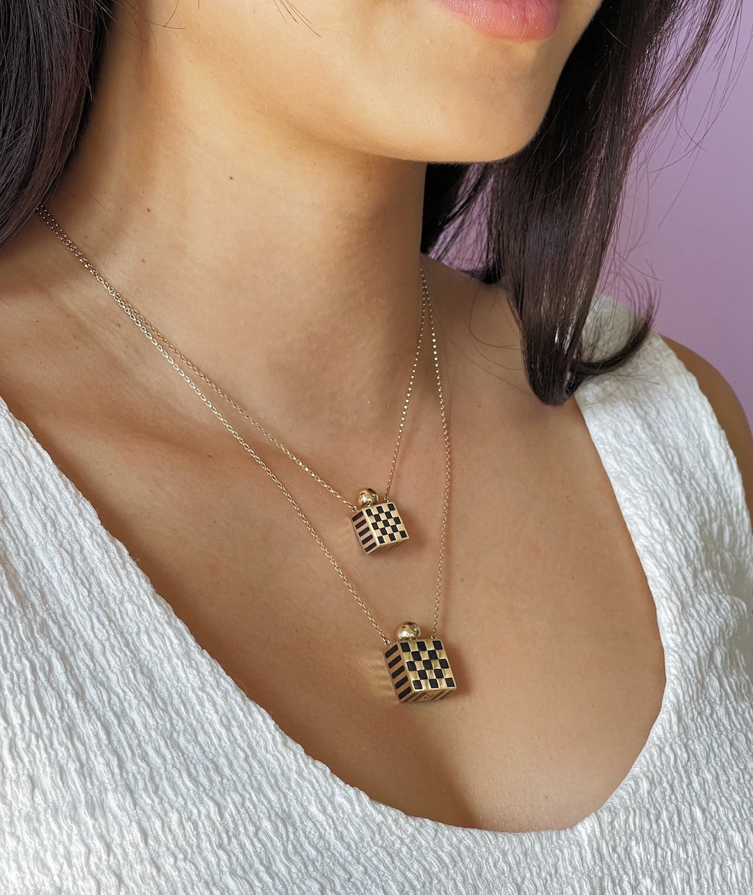 Rachel Quinn Jewelry small and large square 14k yellow gold and black checkered enamel memorial vessel box necklaces for ashes on gold chains worn layered on female model neck