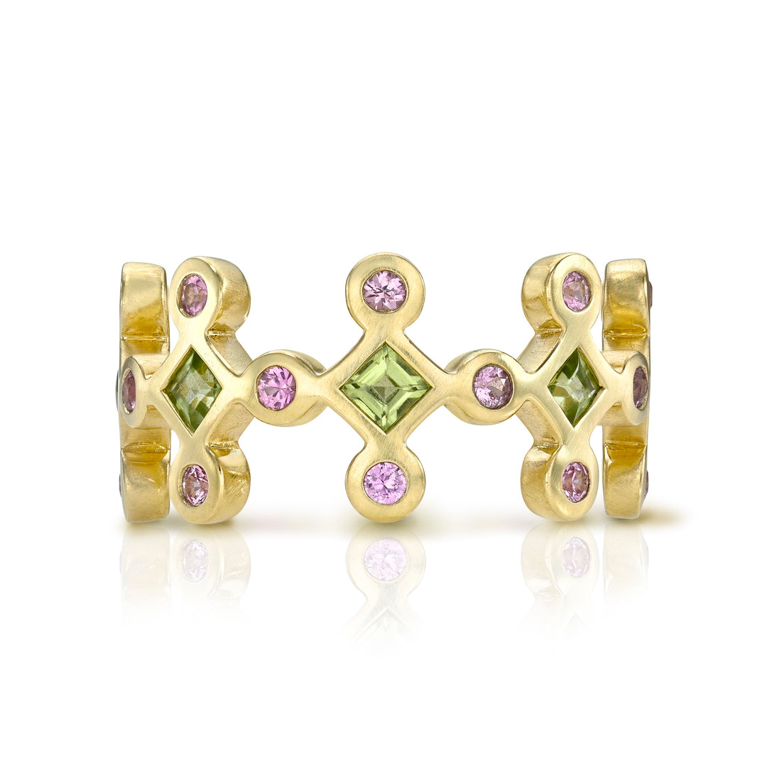 Yellow gold ring with green and pink gemstones on a white background