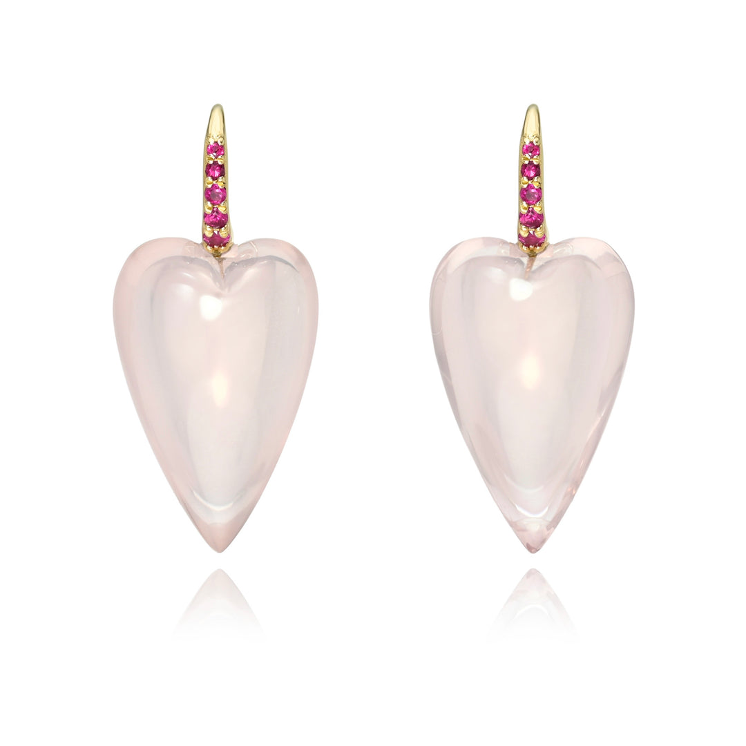 A pair of elongated heart earrings in pale pink rose by Rachel Quinn accented by pink sapphires in the gold ear wires, shown on a white background with a soft reflection.