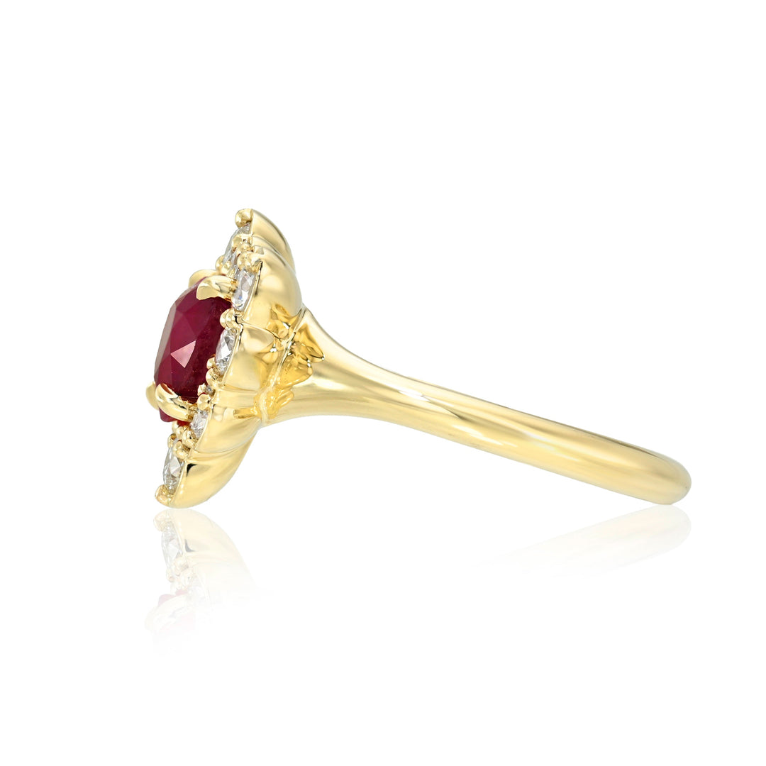 Side view of a gold ring with a red gemstone and diamonds on a white background