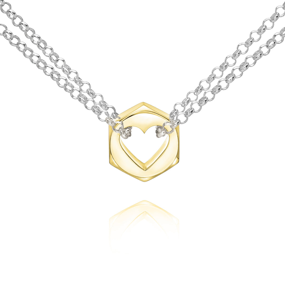 Close up of a yellow gold hex nut pendant with silver chains holding it from either side on a white background