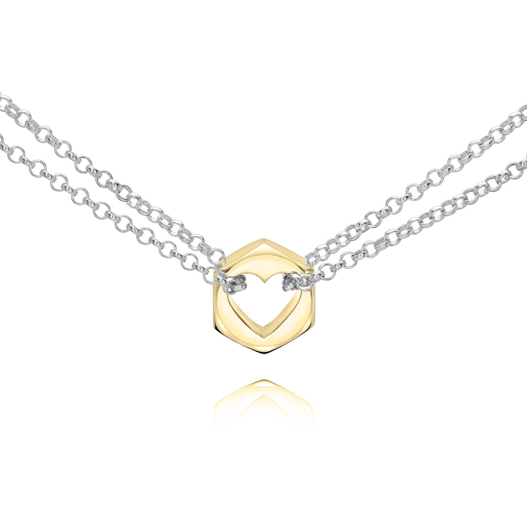 Close up of a yellow gold hex nut pendant with silver chains holding it from either side on a white background