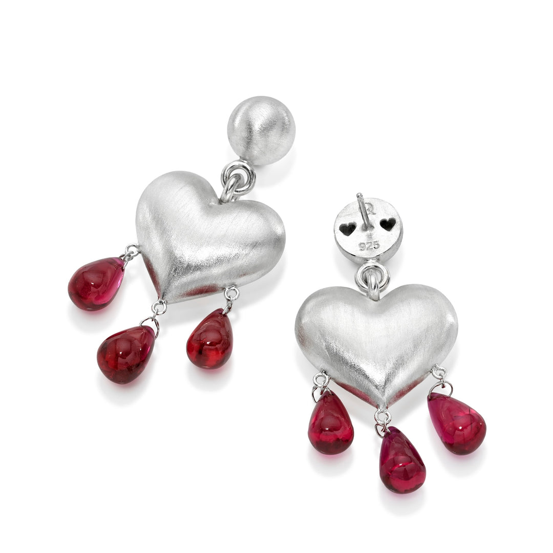 Silver heart-shaped earrings with red teardrop charms on a white background