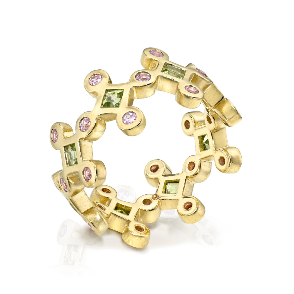 Yellow gold ring with green and pink gemstones on a white background