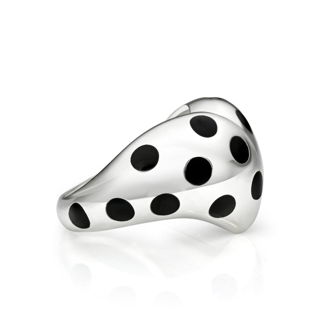Side view of silver heart ring with black polka dots against a white background.