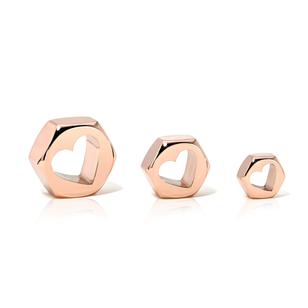 Set of three rose gold hex nut charms in sizes large, medium, and small with heart-shaped center holes on a white background