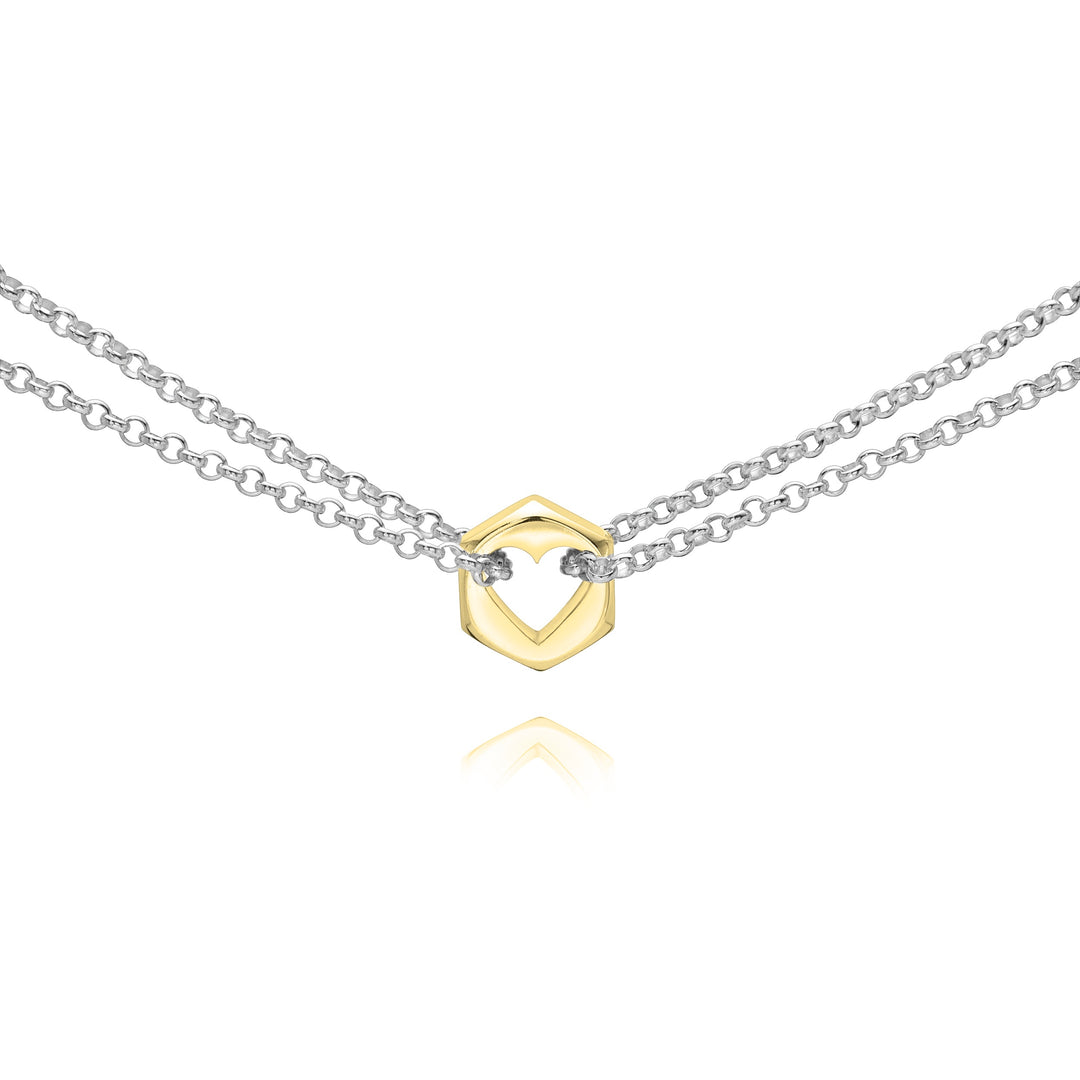 Close up of a yellow gold hex nut charm with silver chains holding it from either side on a white background