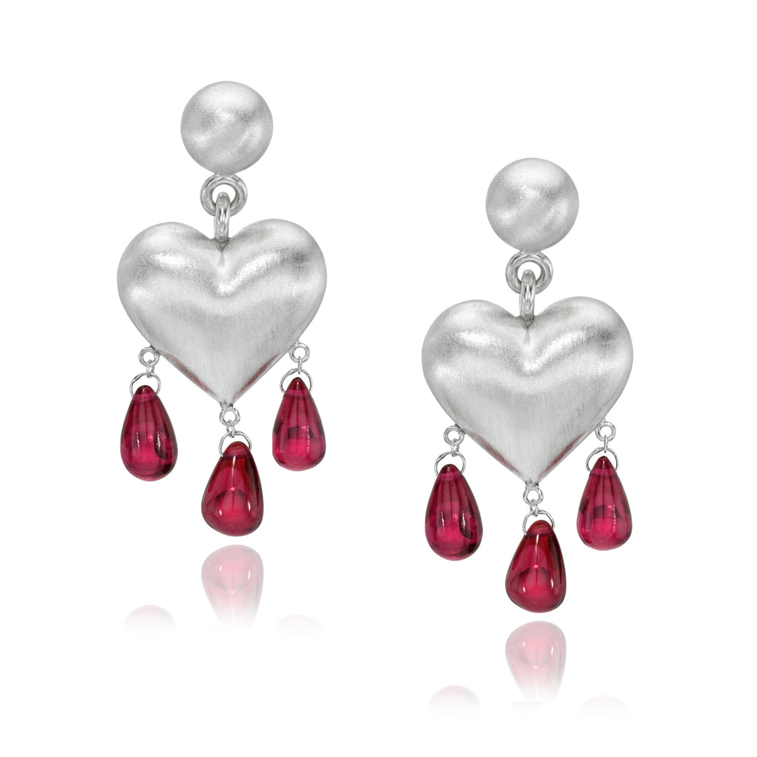 Silver heart-shaped earrings with red teardrop charms on a white background
