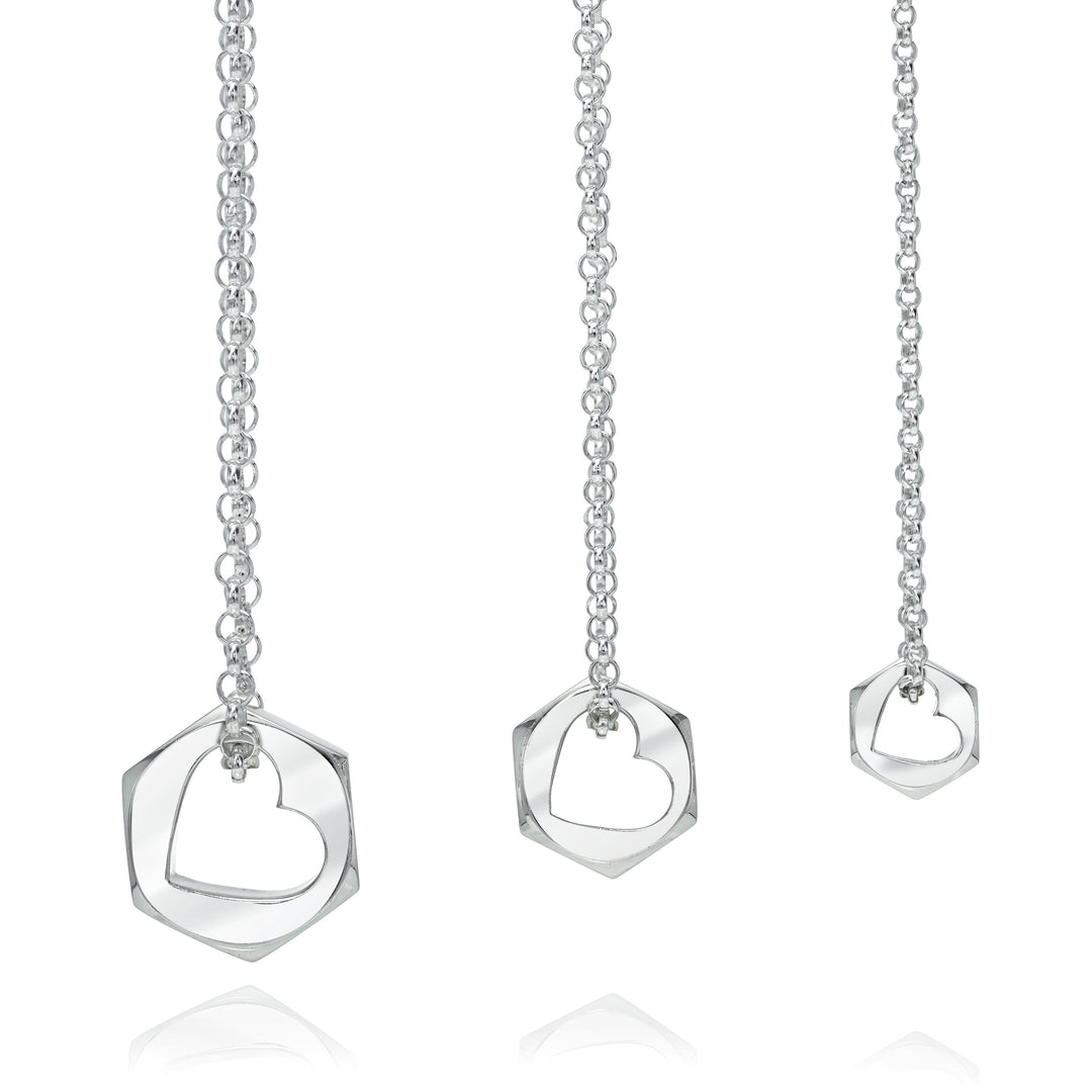 Silver necklace with hex nut shape pendant with a heart shaped opening on a white background