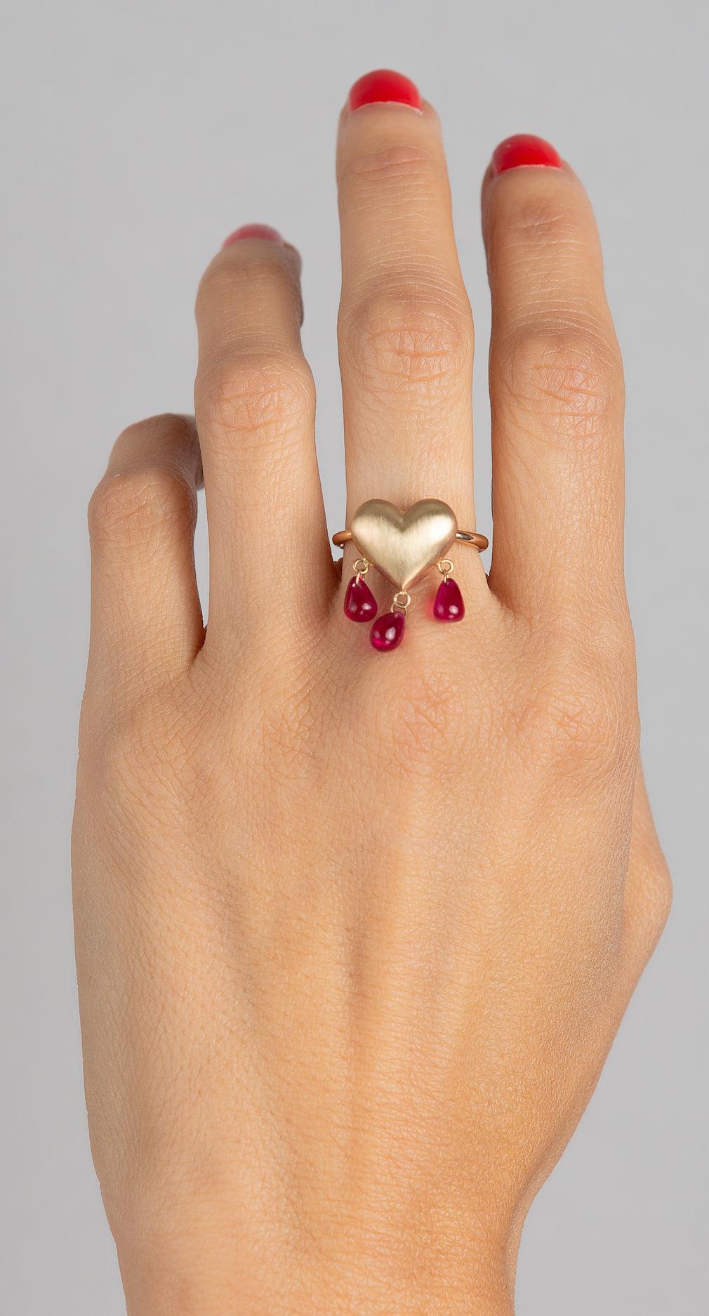 14k gold puffy heart ring with 3 ruby droplets dangling from heart on model hand