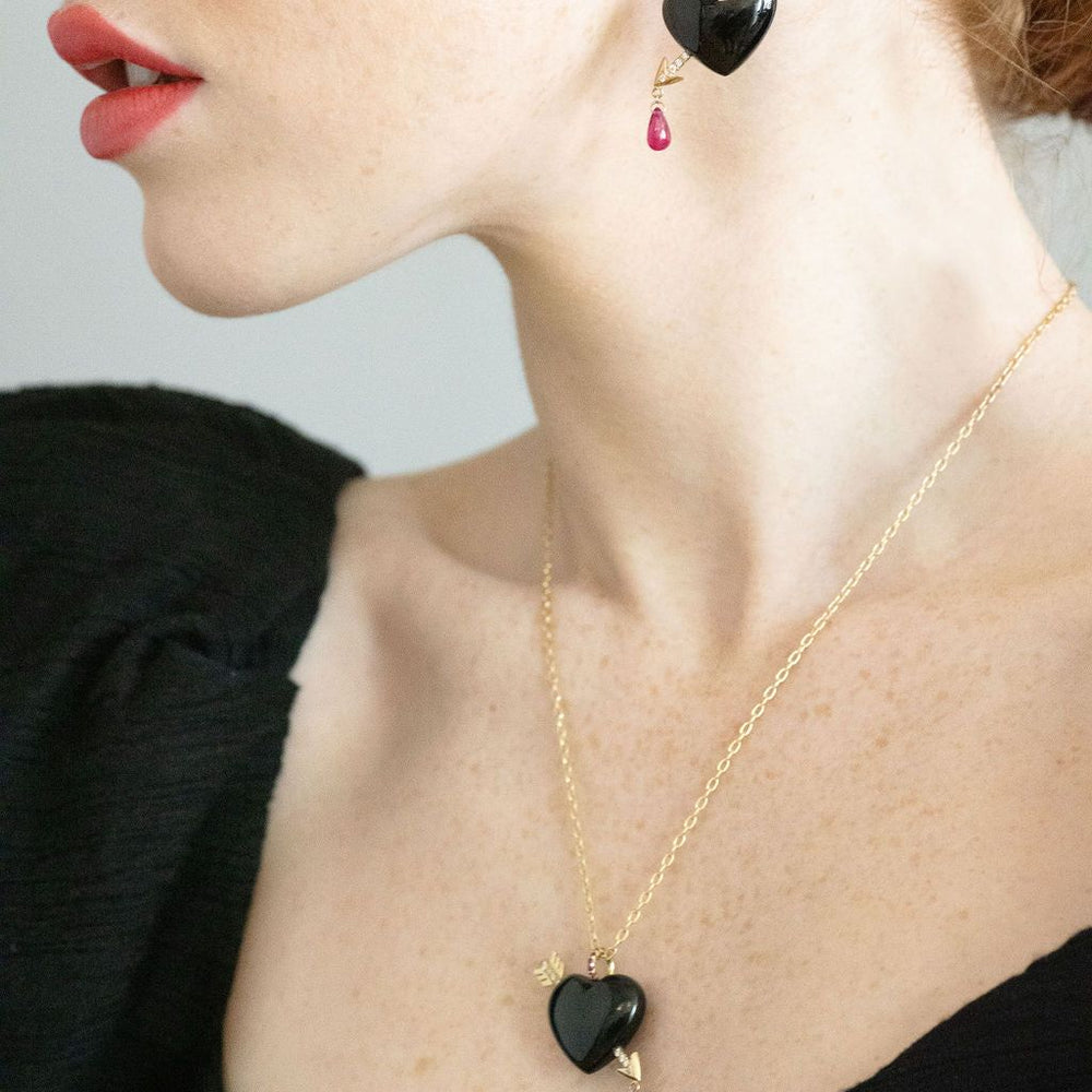 model wearing black heart arrow earrings along with matching necklace