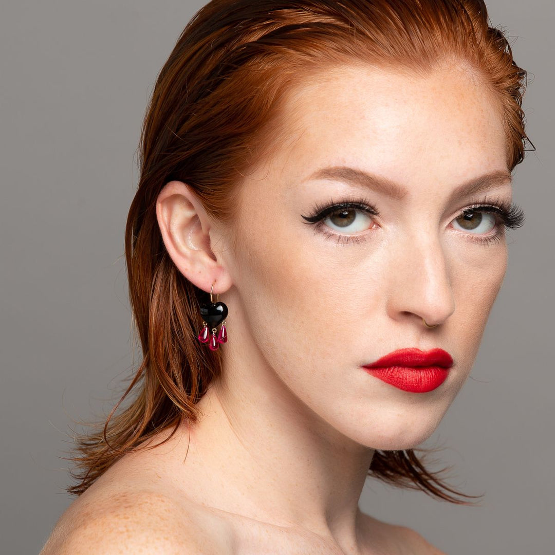 red head wearing onyx bleeding heart earring on grey background