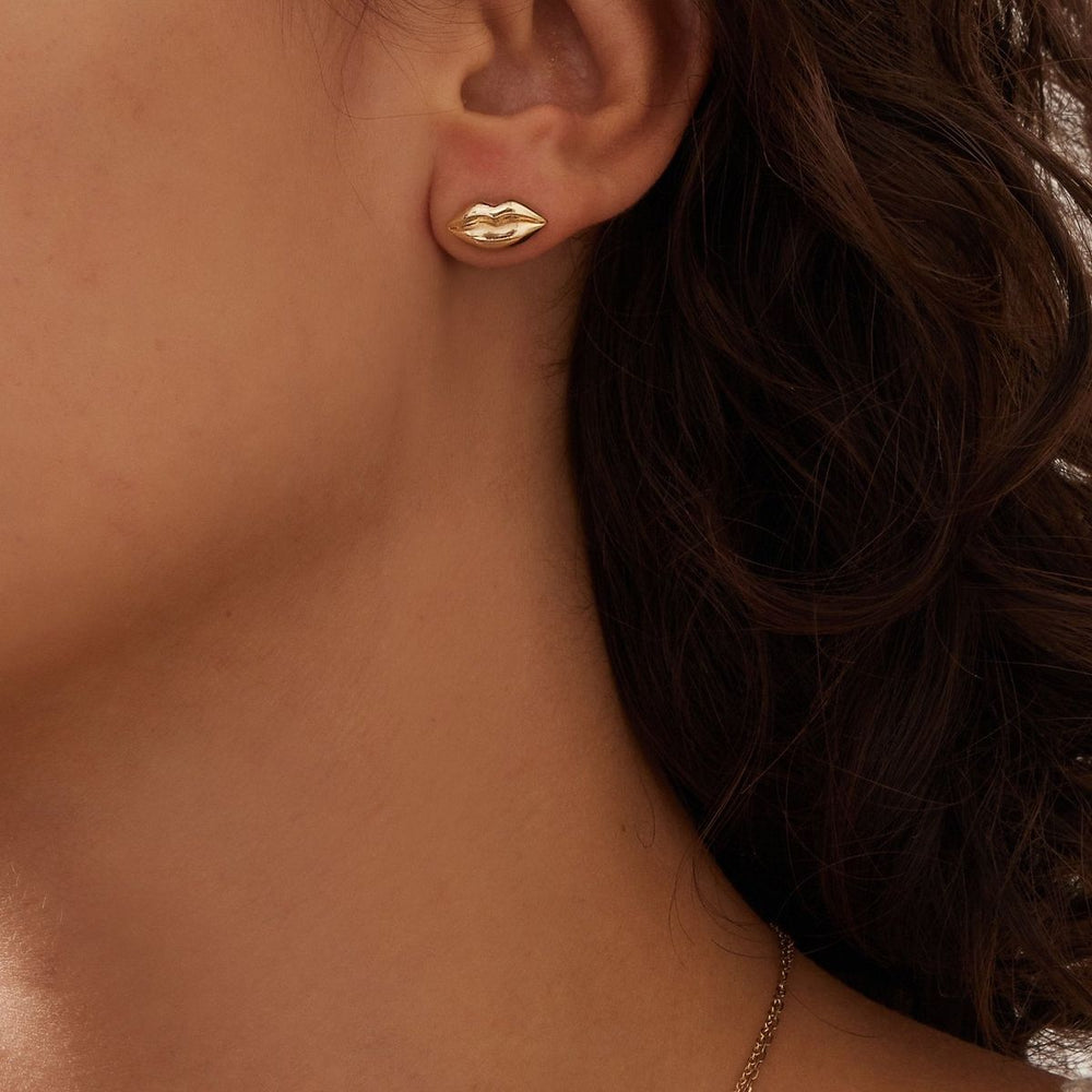 close up of a brunette woman's neck and ear wearing a small yellow gold lips stud