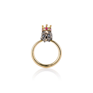 gold ring with blackened royal skull head with gold tooth adorning a ruby and diamond crown front view on white background