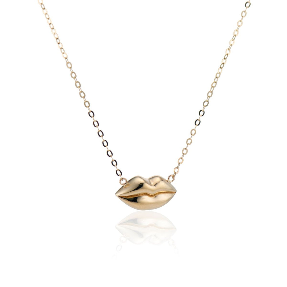 angled view of gold lips on a gold chain necklace with a white background
