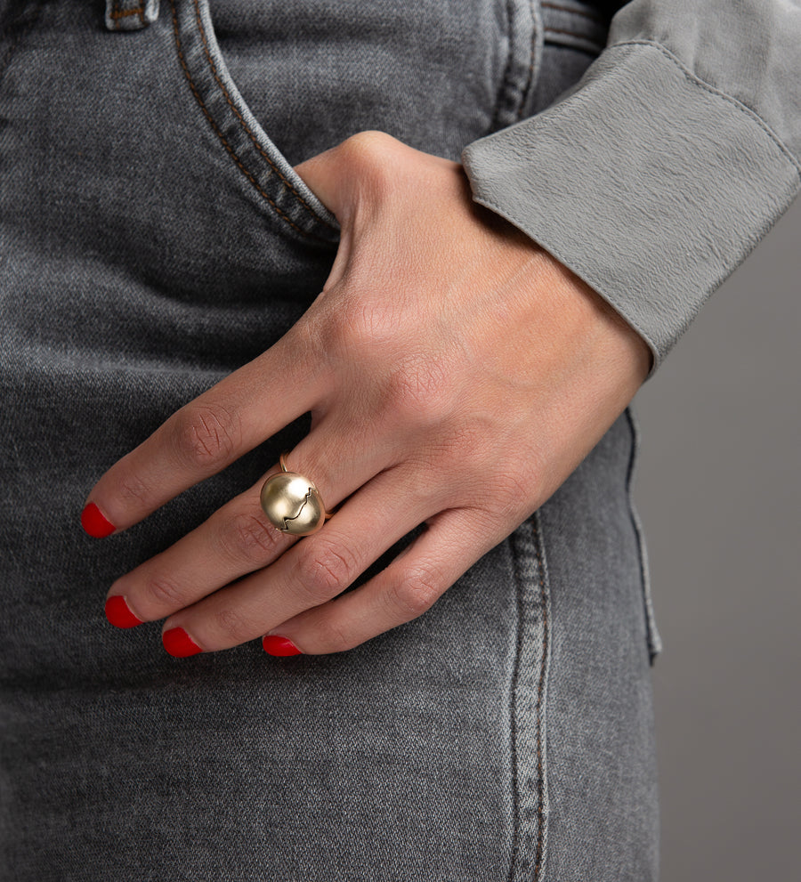 Woman in grey jeans and blouse wearing yellow gold egg ring on hand with thumb the the pocket