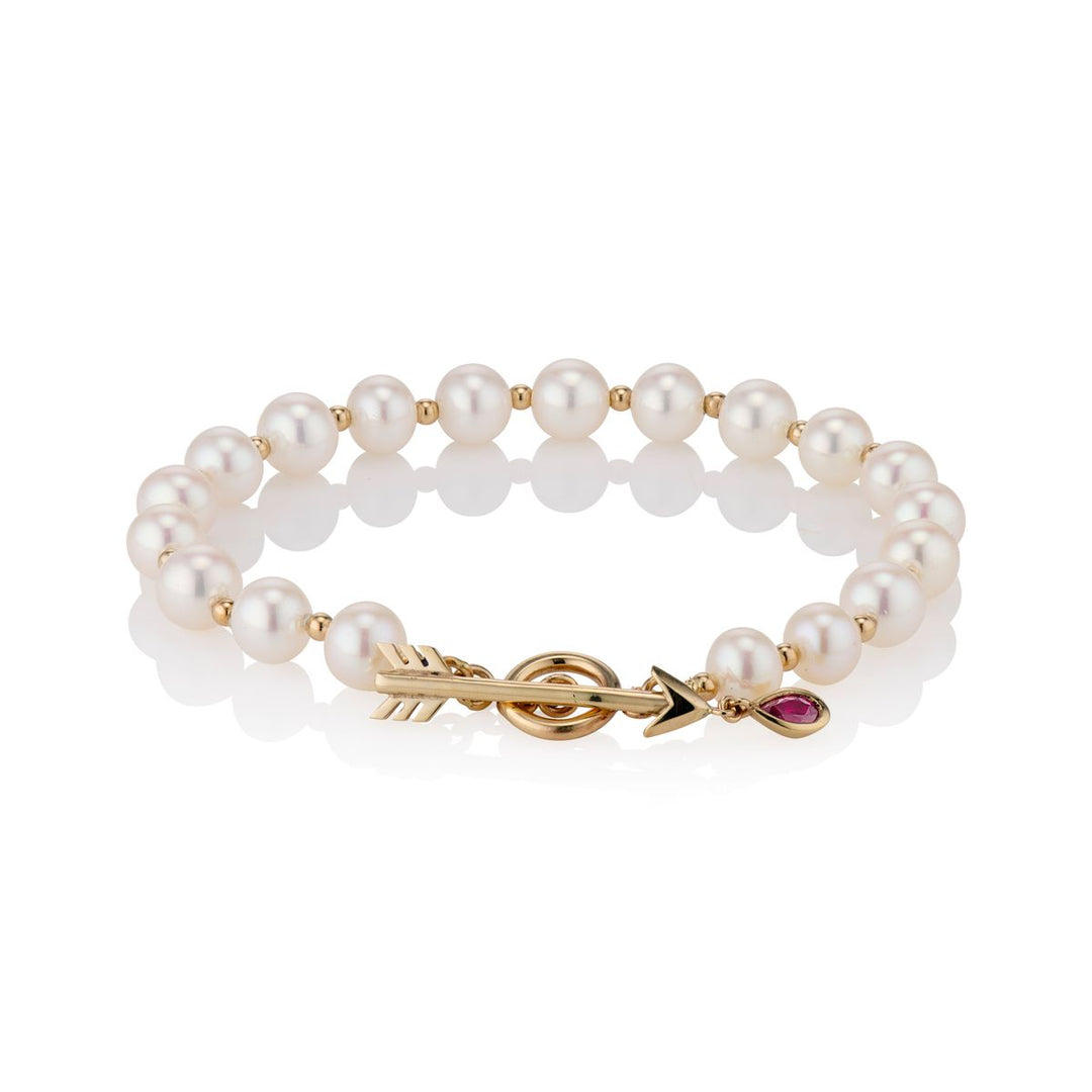 pearl and gold alternating bracelet chain with gold arrow closure with red ruby droplet on arrow point, on a white background