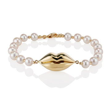 gold lip bracelet on a pearl and gold chain on a white background