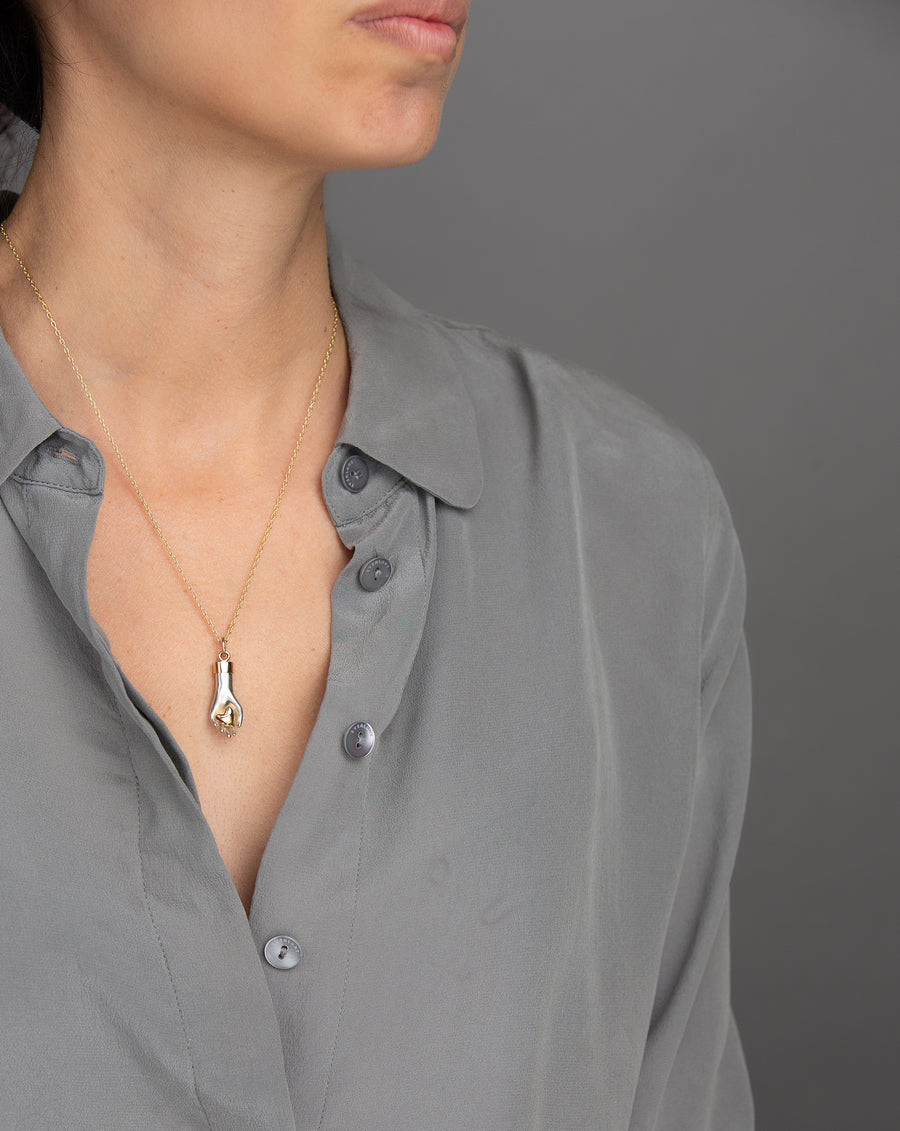 woman in grey modeling solid sterling silver hand gently hold a 14K rose gold heart with yellow gold bail on yellow gold chain necklace