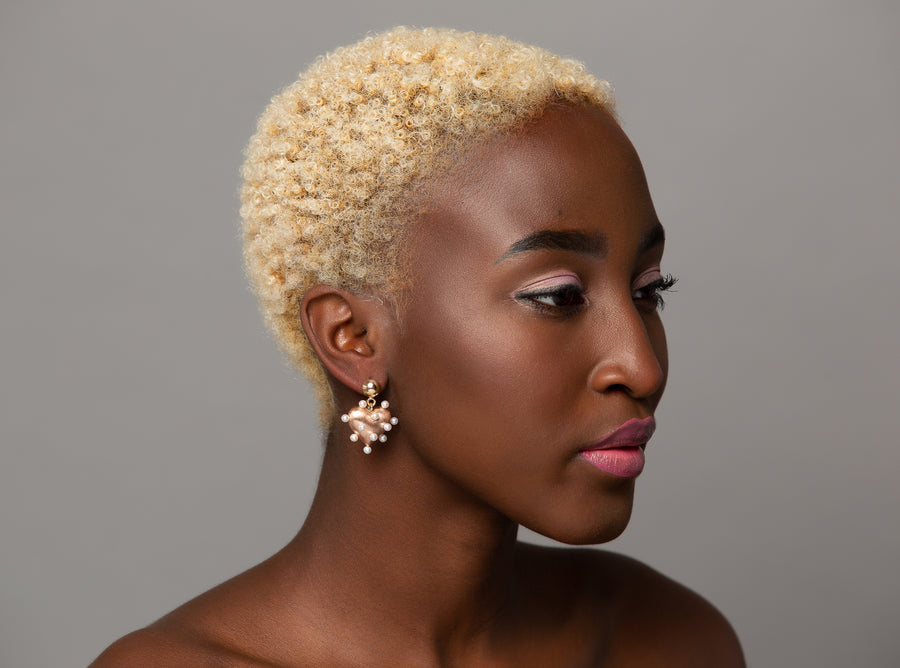woman modeling 3-dimensional 14K rose gold brushed puffy heart earrings are embellished with freshwater pearl 