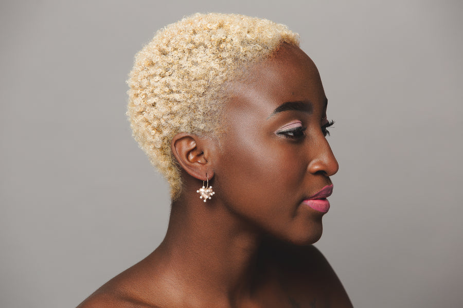 woman modeling a single petite rose gold brushed puffy heart earring with freshwater pearls all around with yellow gold ear wire