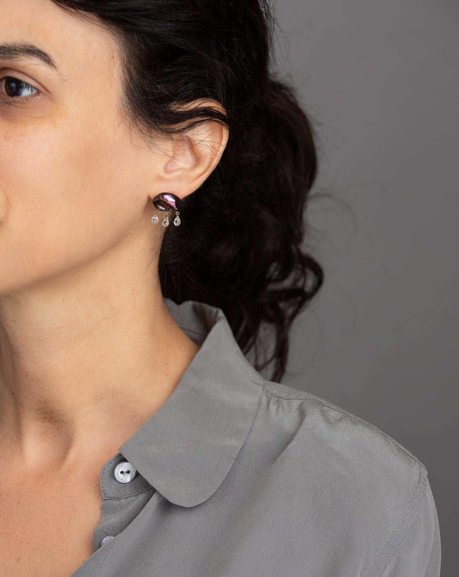 woman in grey modeling dark peacock keshi pearl earring in cloud-like form with three white topaz dangling from the bottom with yellow gold components