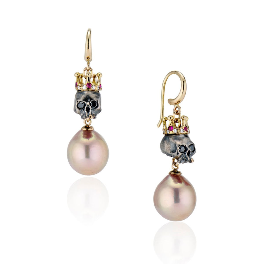 set of regal skull earrings are bejeweled with 14K gold crowns set with brilliant cut rubies and diamonds all around. Twinkling black diamond eyes and a single front gold tooth set on a white background