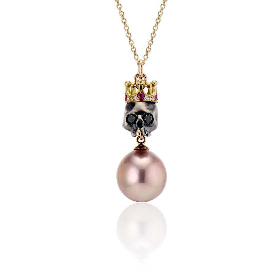royal skull necklace with pink pearl is bejeweled with a 14K gold crown set with brilliant cut rubies and diamonds all around. Twinkling black diamond eyes and a single front gold tooth on yellow gold chain
